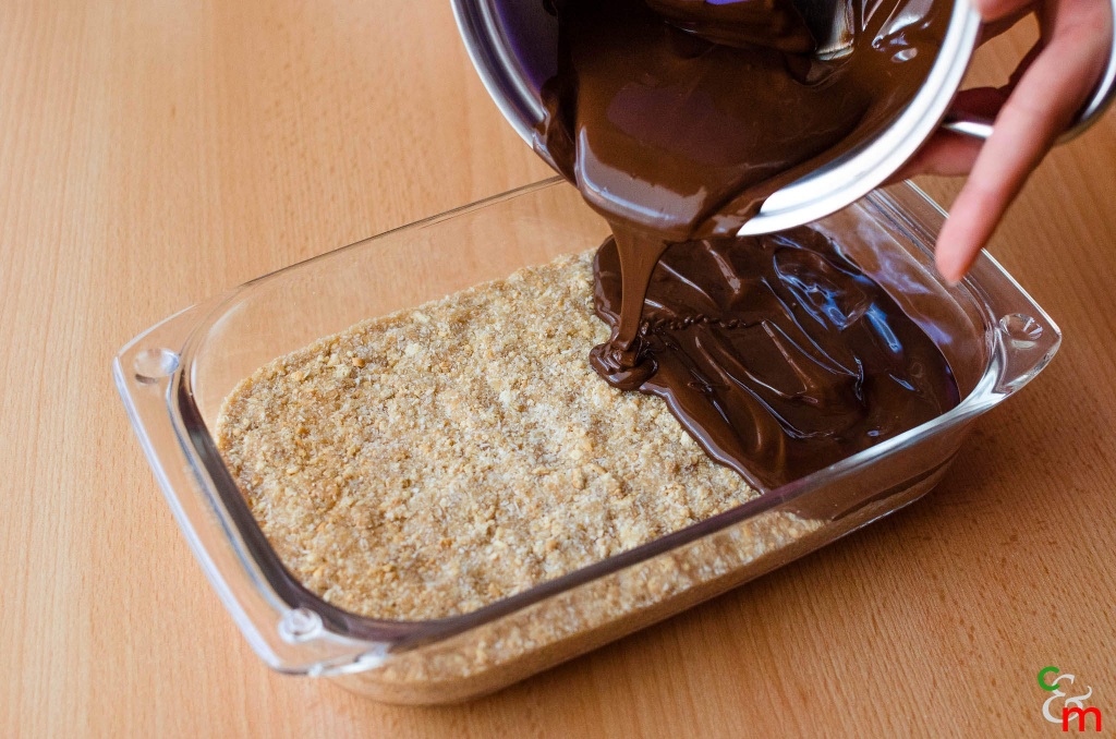 Versate il composto in una pirofila e ottenete uno strato compatto. Versate sopra il cioccolato sciolto.