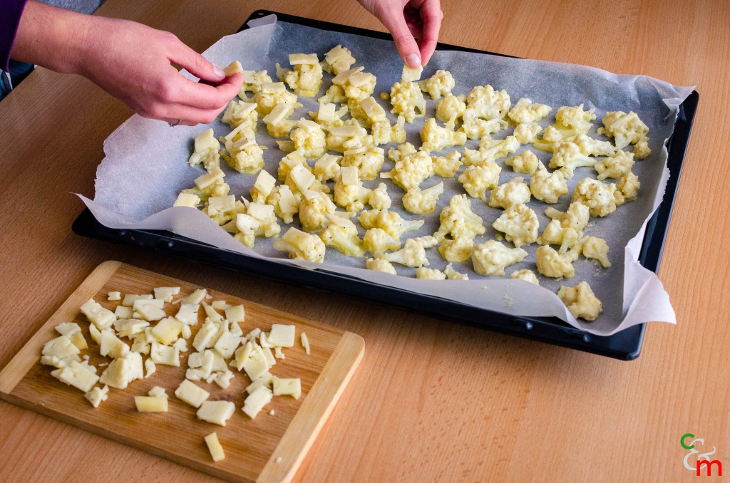 Mettete i pezzi di cavolfiore su una teglia da forno ricoperta di carta da forno, e posate un pezzetto di formaggio su ogni pezzo.